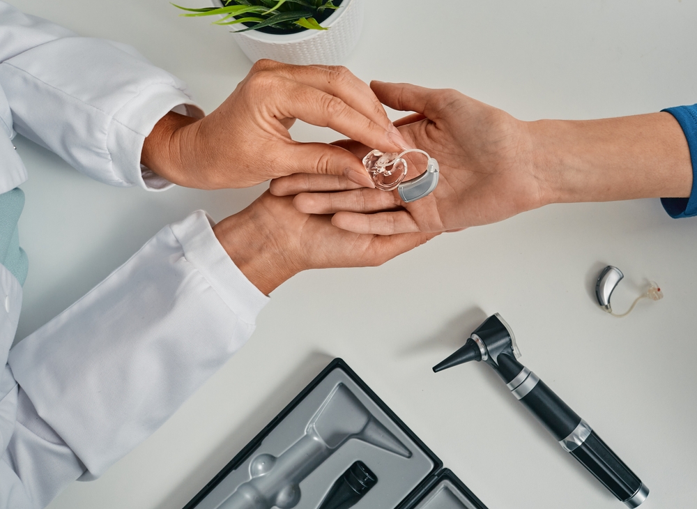 Audiologist puts modern BTE hearing aid in patients' hand.