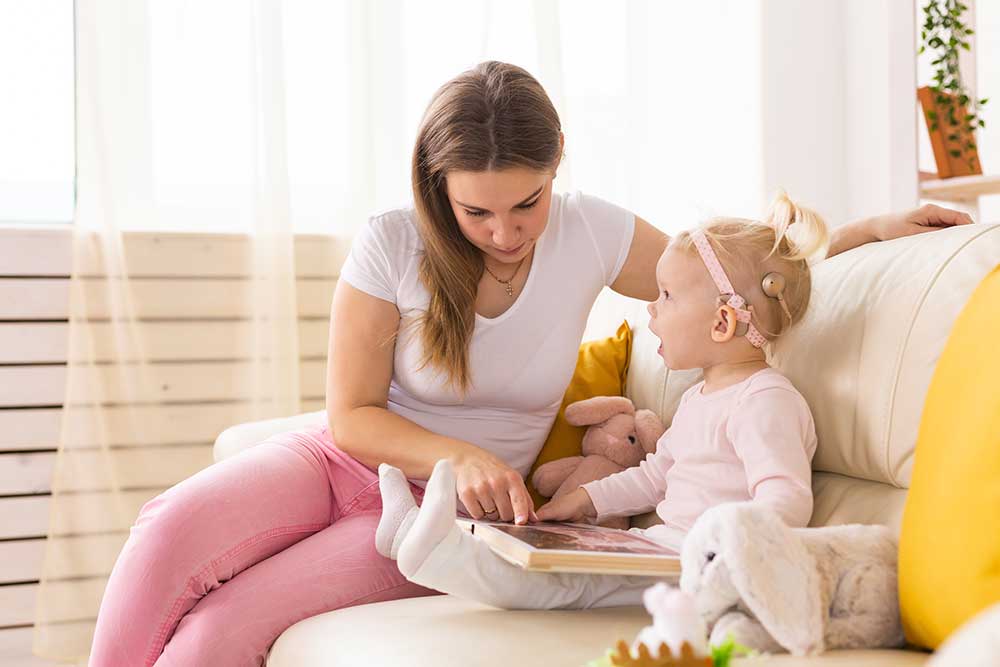 Woman reading to a baby with cochlear implants while sitting on the couch