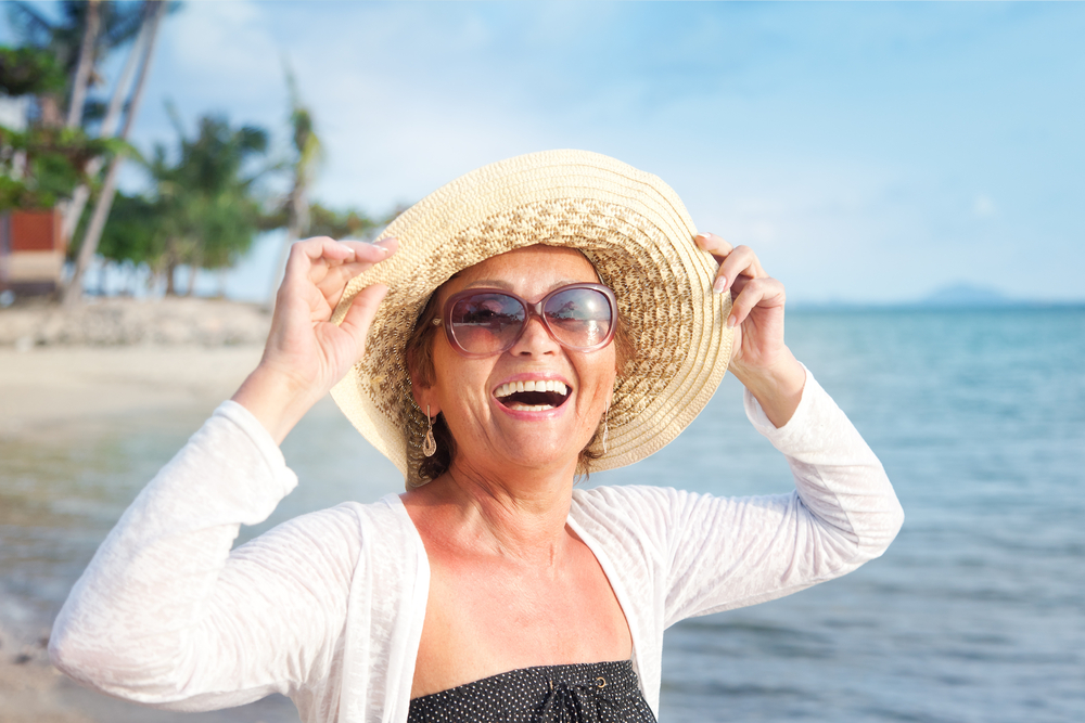 Smiling woman with sun hat on the beach